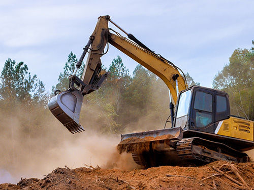 a large digger on the top of earth with trees behind
